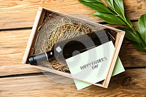 Bottle of wine in box with greeting card for Father\'s Day on wooden background