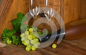 A bottle of wine with a bunch of grapes and wineglasses