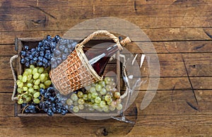 Bottle of wine and bunch of grapes in wooden box on wooden table