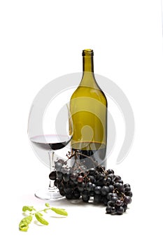 A bottle of wine and bunches of ripe grapes in a glass on a white background