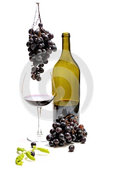 A bottle of wine and bunches of ripe grapes in a glass on a white background