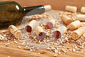 A bottle of wine closed with a stopper on the background of scattered wooden chips and various wine corks