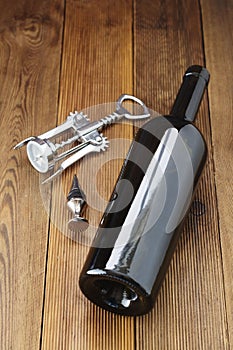 A bottle of wine with corckscrew, wooden rustic background. Flat lay wine drink with copy space