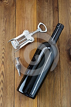 A bottle of wine with corckscrew, wooden rustic background. Flat lay wine drink with copy space