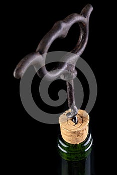 A bottle of wine and a corkscrew on a dark table. Opening good wine with a corkscrew