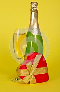 Bottle and wine glass with champagne, a gift box