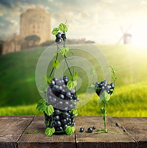 Bottle of Wine and a glass made by of grape leaves and a bunch of grapes on a wooden background