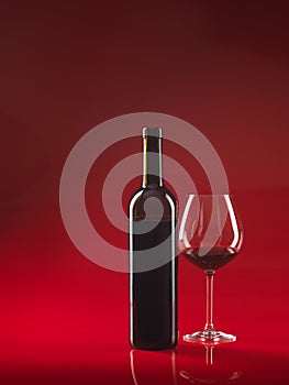 Bottle of wine, glass on red background photo