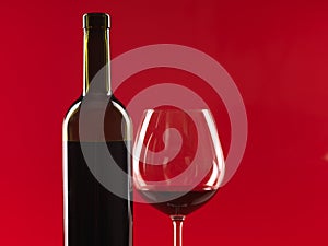 Bottle of wine, glass on red background