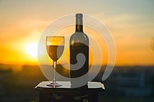 A bottle of wine and glasse on sunset background