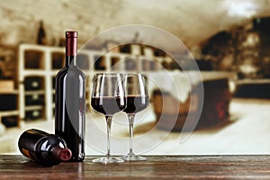 A bottle of wine and glasses with wine on a barrel in a wine cellar