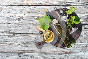 A bottle of wine with glasses and grapes. Leaves of grapes. Top view. On a white wooden background.