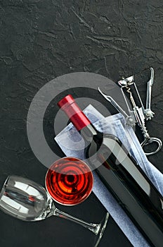 Bottle, wine glasses with wine and corkscrew on dark background