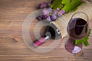 Bottle of wine, red grape and glass on wooden table