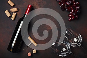 Bottle of wine, two glasses, corkscrew and corks, on rusty background top view