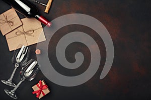 Bottle of wine, two glasses, gift box, envelope, corkscrew and corks, on rusty background top view