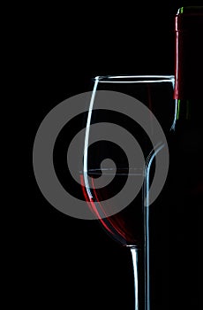 Bottle and wineglass with red wine close up on white background