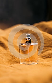 A bottle of women`s fragrant perfume on a brown textured fabric background