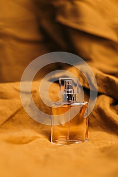 A bottle of women`s fragrant perfume on a brown textured fabric background