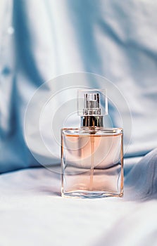 A bottle of women`s fragrant perfume on a silk textured fabric background