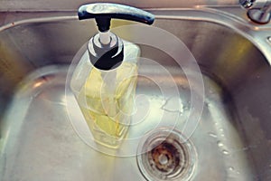 Bottle of yellow dish washing liquid on Stainless steel sink