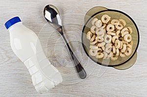 Bottle of yogurt, oat flakes in brown bowl, spoon