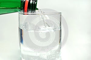 Bottled mineral water and glass on a white background