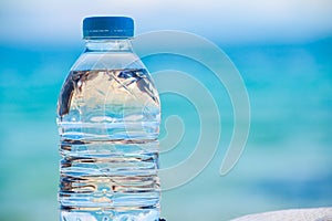 Bottled water on a hot day at the beach.Plastic bottle with clear water to drink, on sea background. bottle of water on