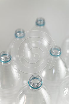 Bottlenecks of a pack of liter and a half of empty mineral water without caps just with the blue sealing ring on a white