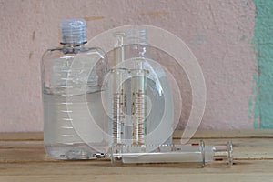 Bottles of alcohol gel and syringes on wooden background