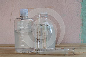 Bottles of alcohol gel and syringes on wooden background