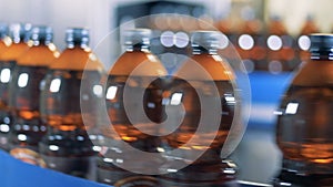 Bottles with beer moving on a line in row, close up.