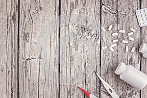 Bottles and blisters with pills and thermometers on wooden background. Top view. Copy space for text