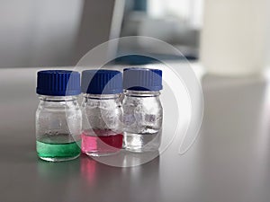 Bottles and blue cap with green, red and clear solution buffer pH 4, 7 and 10 on bench laboratory for analysis and calibrate.