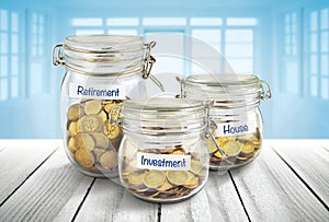 Bottles of cash with coins on wooden table, for saving and banking finance concept