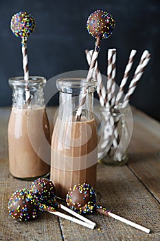 Bottles of chocolate milk with straws and cake pops