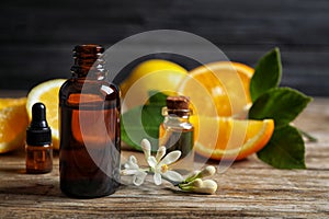 Bottles of citrus essential oil on wooden table. Space for text