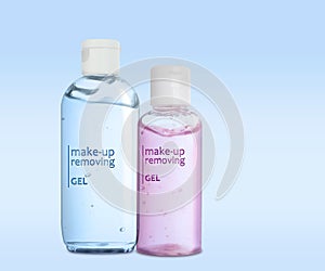 Bottles of cleansing gels on light blue background. Makeup remover