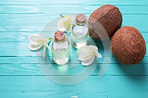 Bottles with coconut oil on bright wooden background.