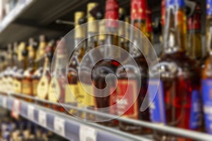 Bottles of cognac from different manufacturers on the shelves in the supermarket. Blurred