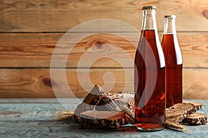 Bottles of delicious fresh kvass, spikelets and bread on blue wooden table. Space for text