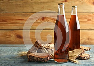 Bottles of delicious fresh kvass, spikelets and bread on blue wooden table. Space for text