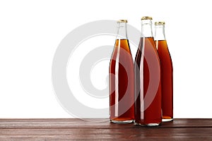 Bottles of delicious kvass on wooden table against white background
