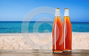 Bottles of delicious kvass on wooden table near sea. Space for text