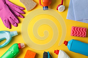 Bottles with detergent and cleaning supplies on yellow background