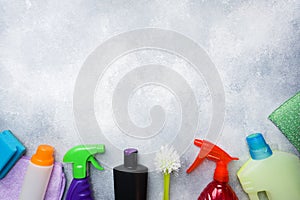 Bottles with detergents, brushes and sponges on concrete background. Colorful cleaning products. Home cleaning concept. Top view,