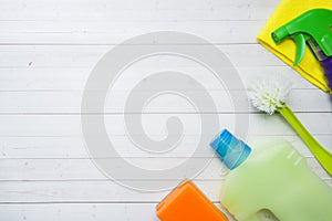 Bottles with detergents, brushes and sponges on wooden background. Colorful cleaning products. Home cleaning concept. Top view,