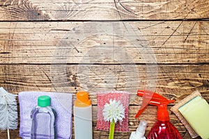 Bottles with detergents, brushes and sponges on wooden background. Colorful cleaning products. Home cleaning concept. Top view,