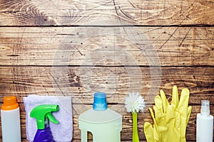 Bottles with detergents, brushes and sponges on wooden background. Colorful cleaning products. Home cleaning concept. Top view,