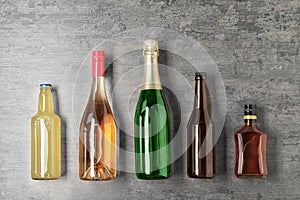 Bottles with different alcoholic drinks on grey background
